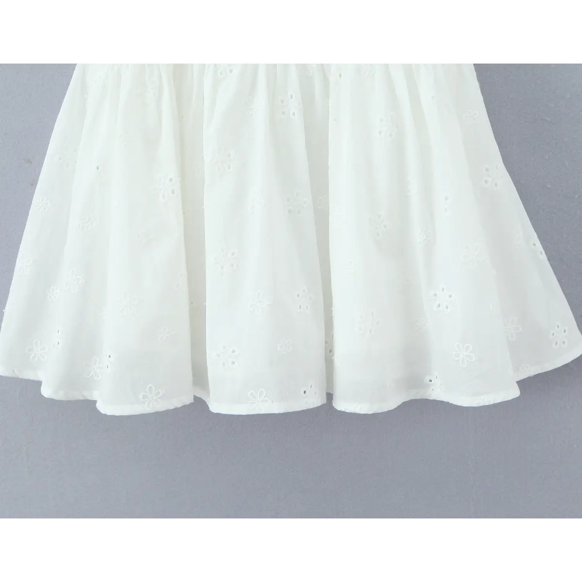 Full view of the gathered skirt, displaying the all-over floral eyelet embroidery and flared silhouette.