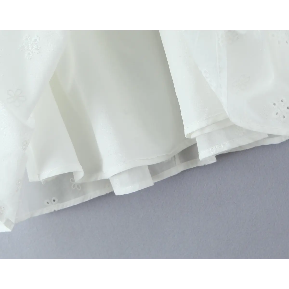 Close-up of the tiered skirt hem, showcasing the floral eyelet embroidery and double-layer construction.