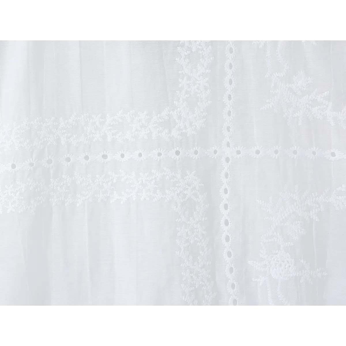 Close-up of the fabric, showcasing the delicate floral and daisy-style embroidery patterns.