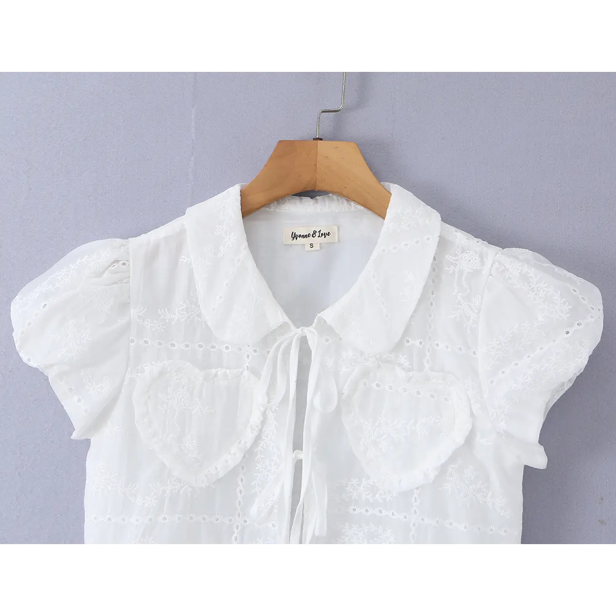 Close-up of the front view, highlighting the Peter Pan collar, tie closure, and heart-shaped embroidered pockets.