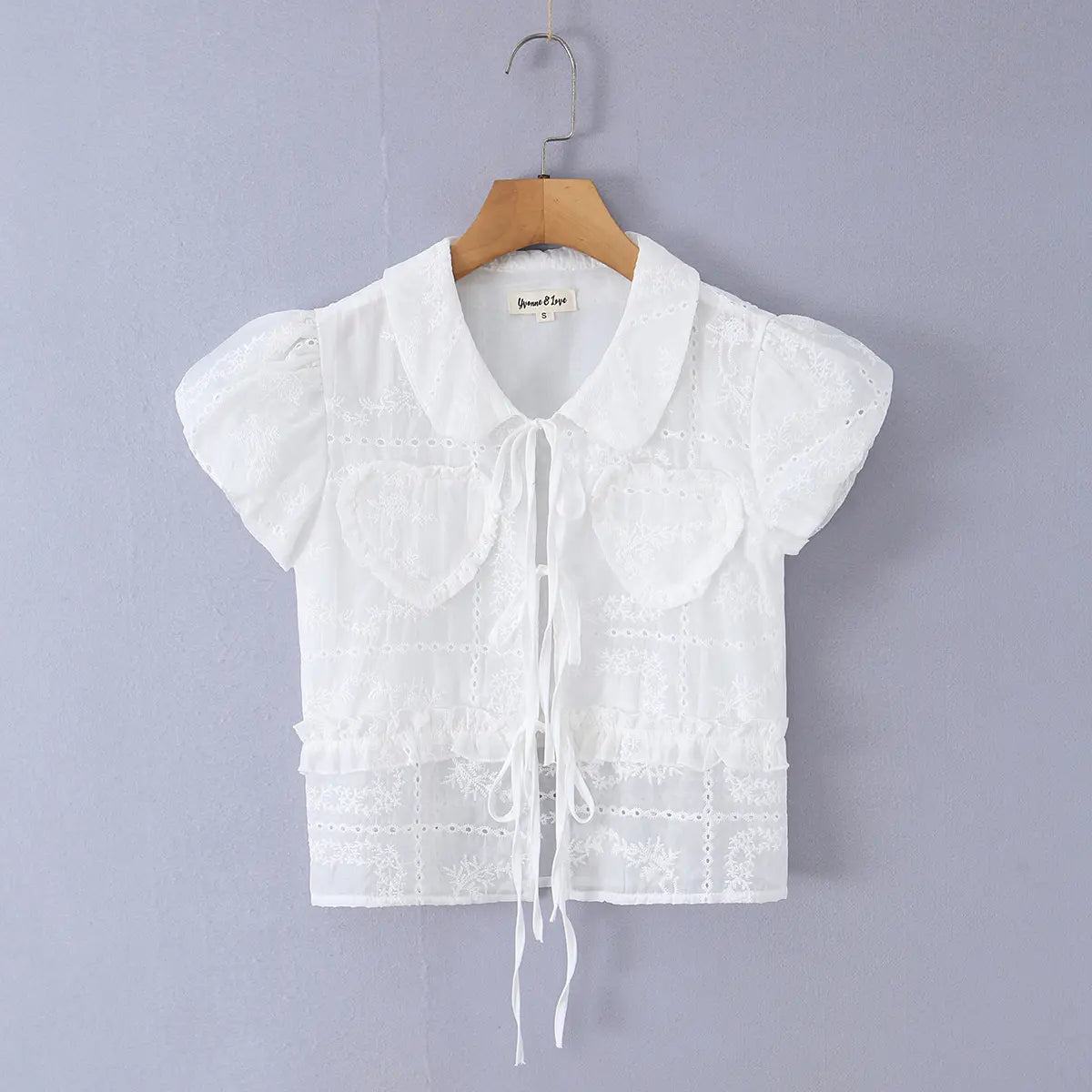 Full front view of the blouse, featuring the tie neckline, heart pockets, and cropped silhouette.