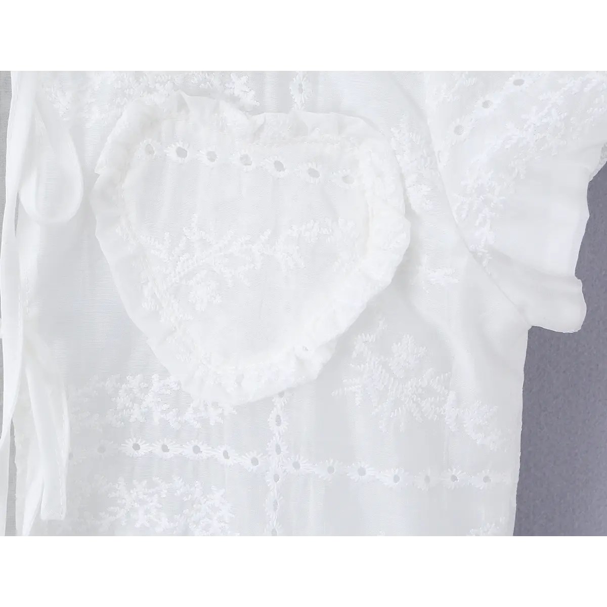 Close-up of the heart-shaped embroidered pocket, showing the scalloped edge and floral embroidery.