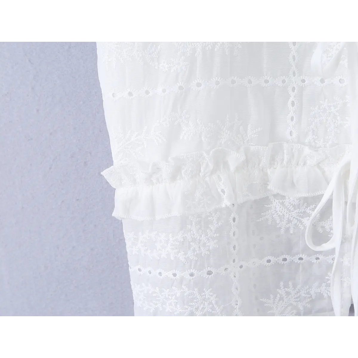 Close-up of the waist ruffle hem, showing the gathered trim and layered embroidery.
