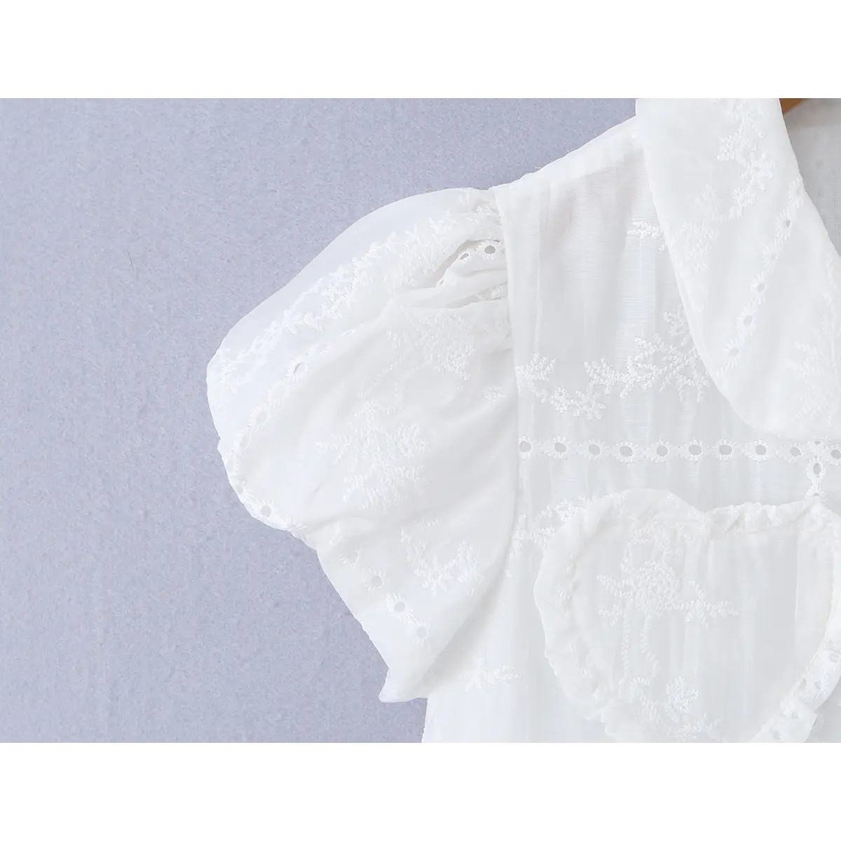 Close-up of the puff sleeve, showing the gathered shoulder and embroidered eyelet trim.