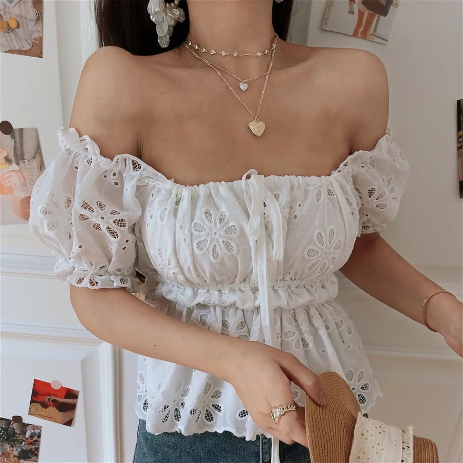 Close-up lifestyle shot of model wearing the white embroidered off-shoulder peplum top