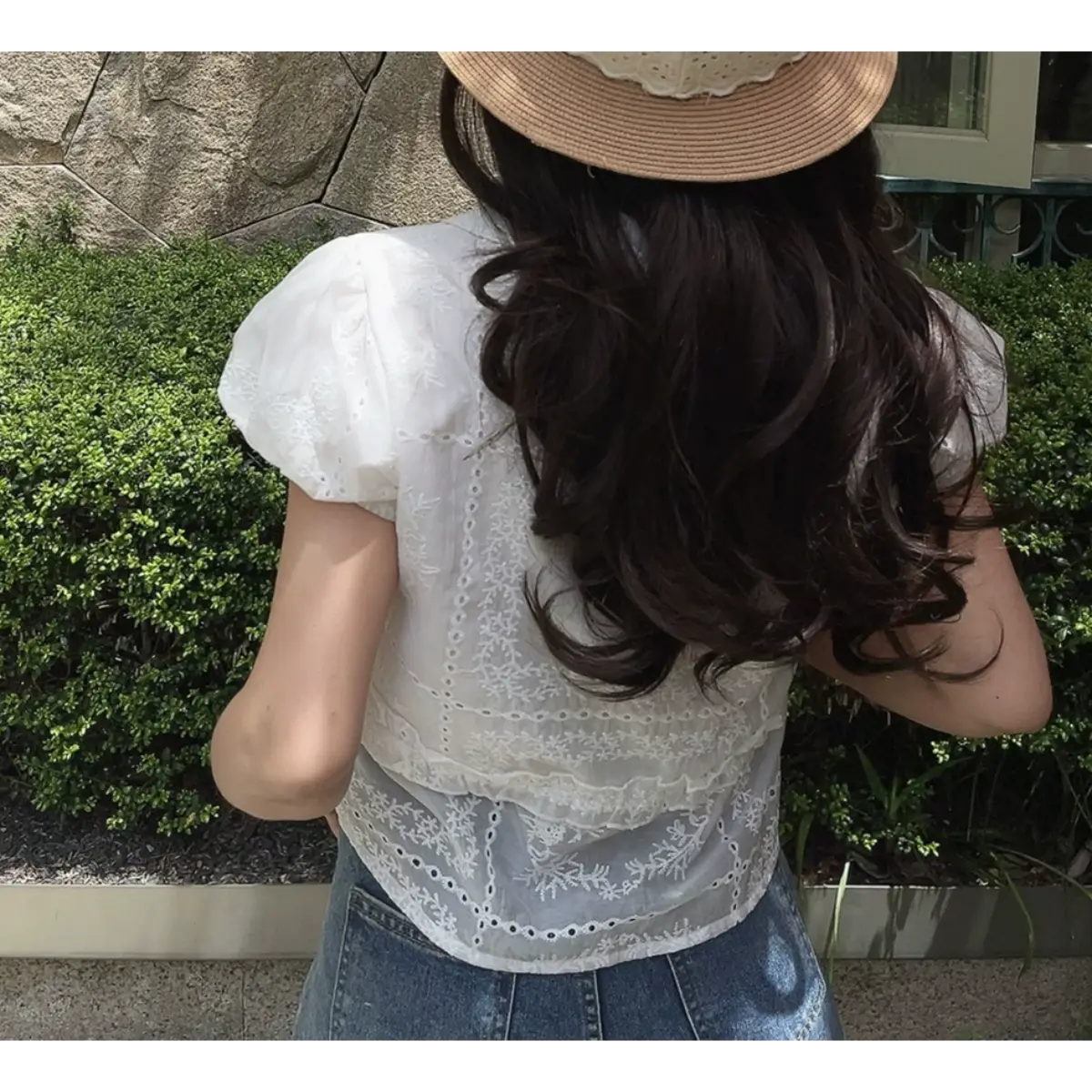 Back view of a white embroidered puff-sleeve blouse with lace details.