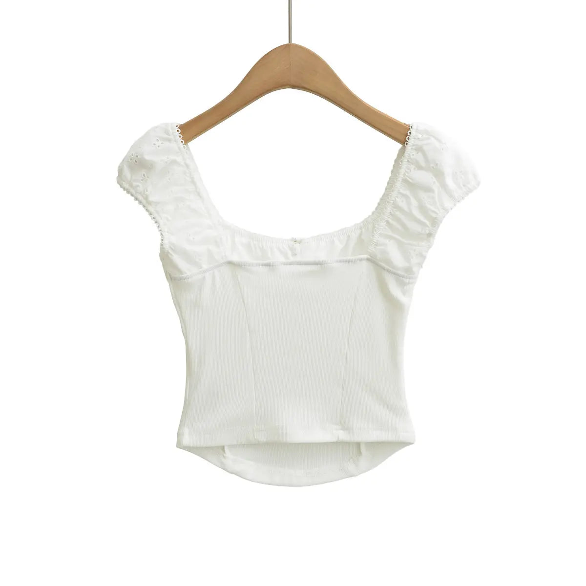 Studio shot of the back of white embroidered ribbed top, featuring ribbed panels and puff sleeve design.

