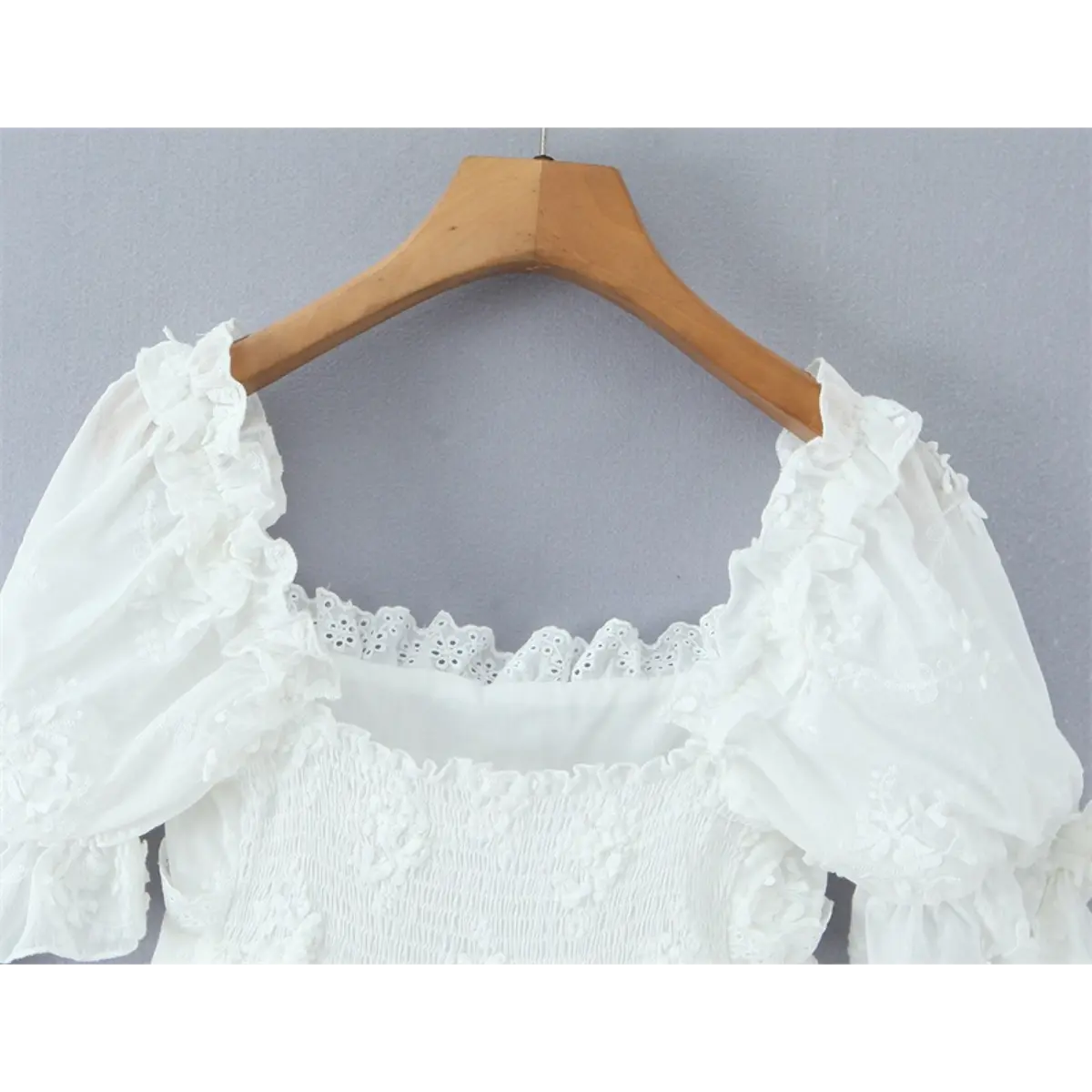 Close-up of the back neckline, eyelet lace trim, and elastic smocked bodice detail.
