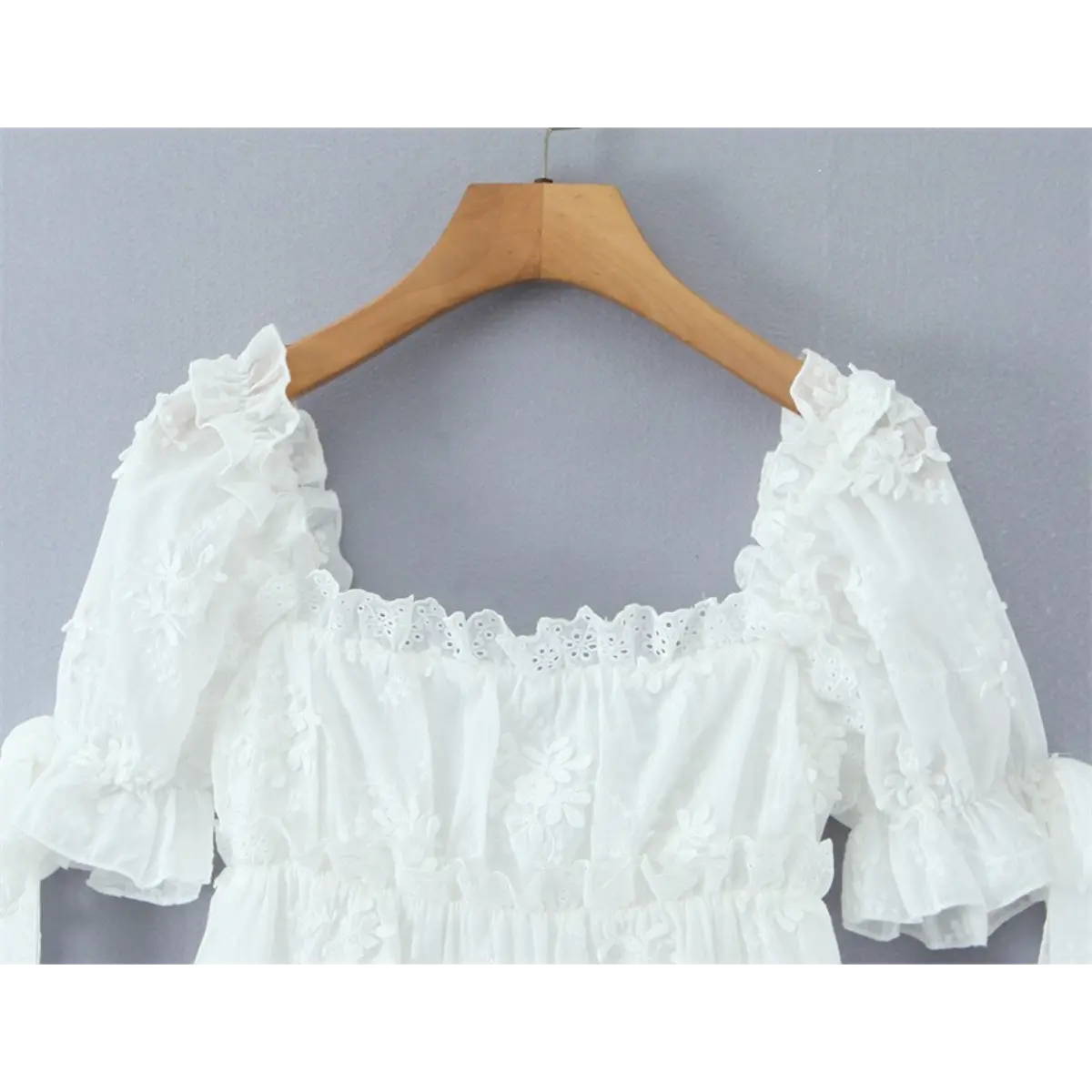 Full view of the dress bodice, featuring the square neckline, lace trim, and gathered puff sleeves.