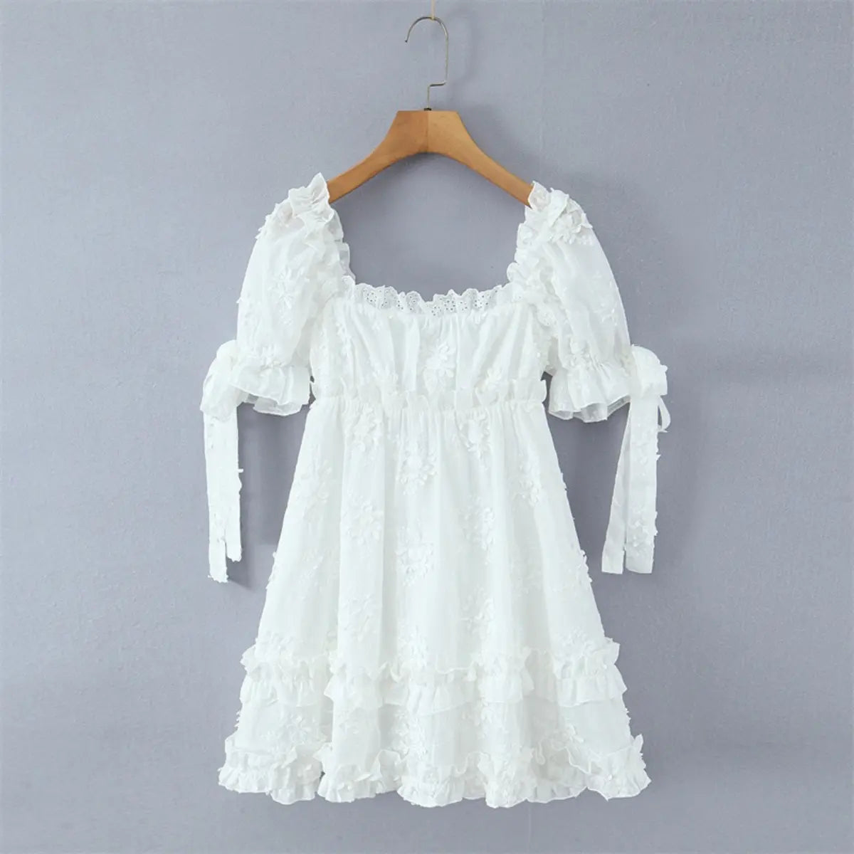 Full view of the dress on a hanger, showing the puff sleeves, waist smocking, and tiered ruffle skirt.