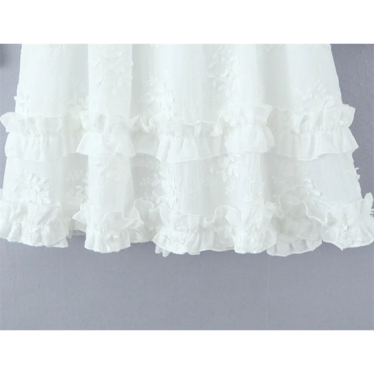 Close-up of the tiered ruffle skirt hem, showcasing floral embroidery and delicate frills.