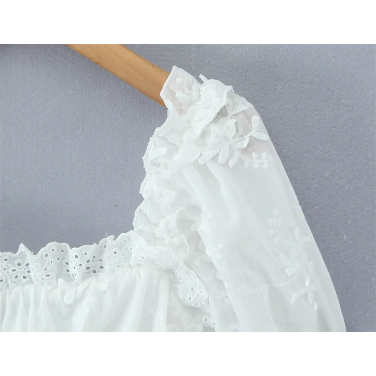 Close-up of the square neckline, eyelet lace trim, and ruffled puff sleeve construction.