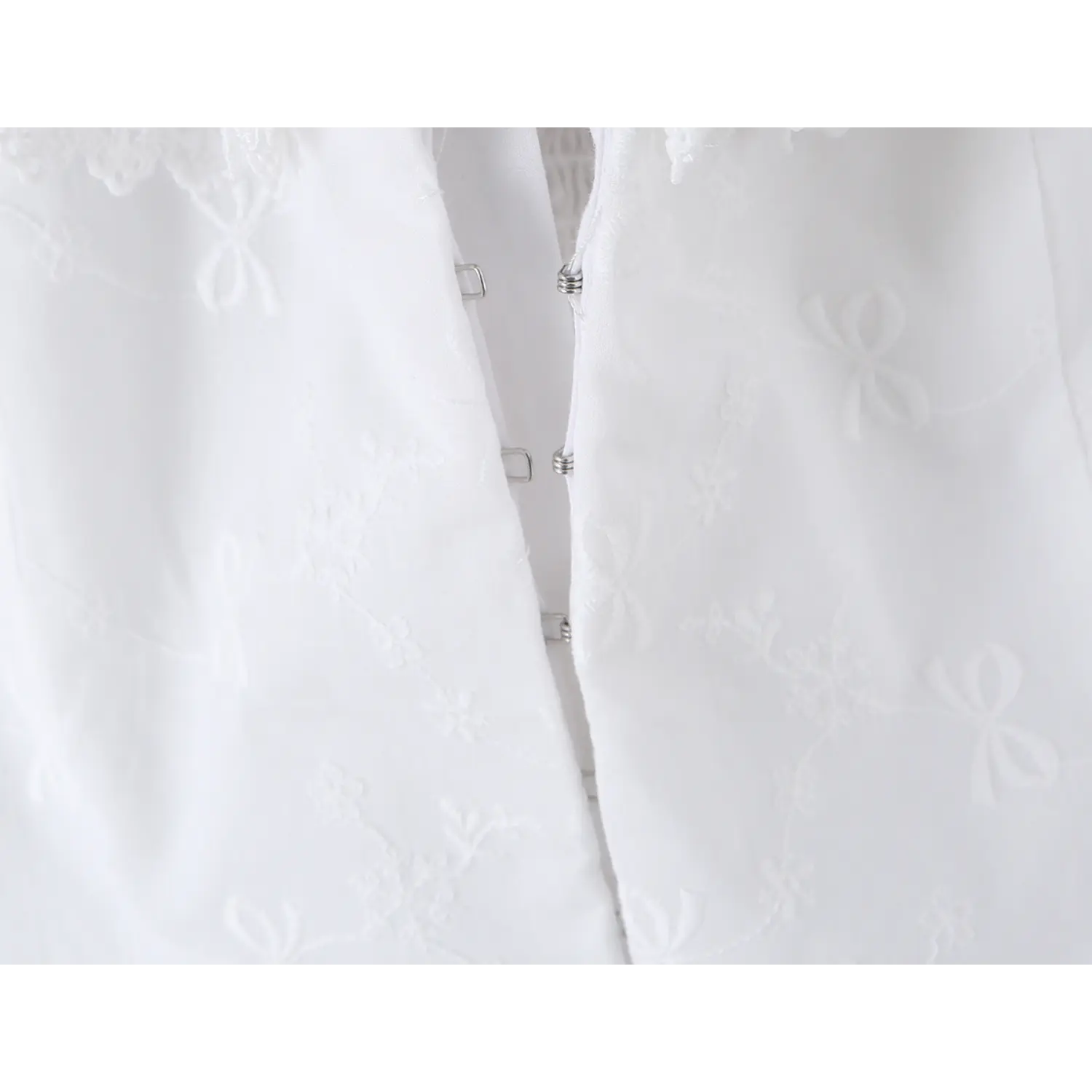 Close-up of the front hook-and-eye closure on the white embroidered camisole