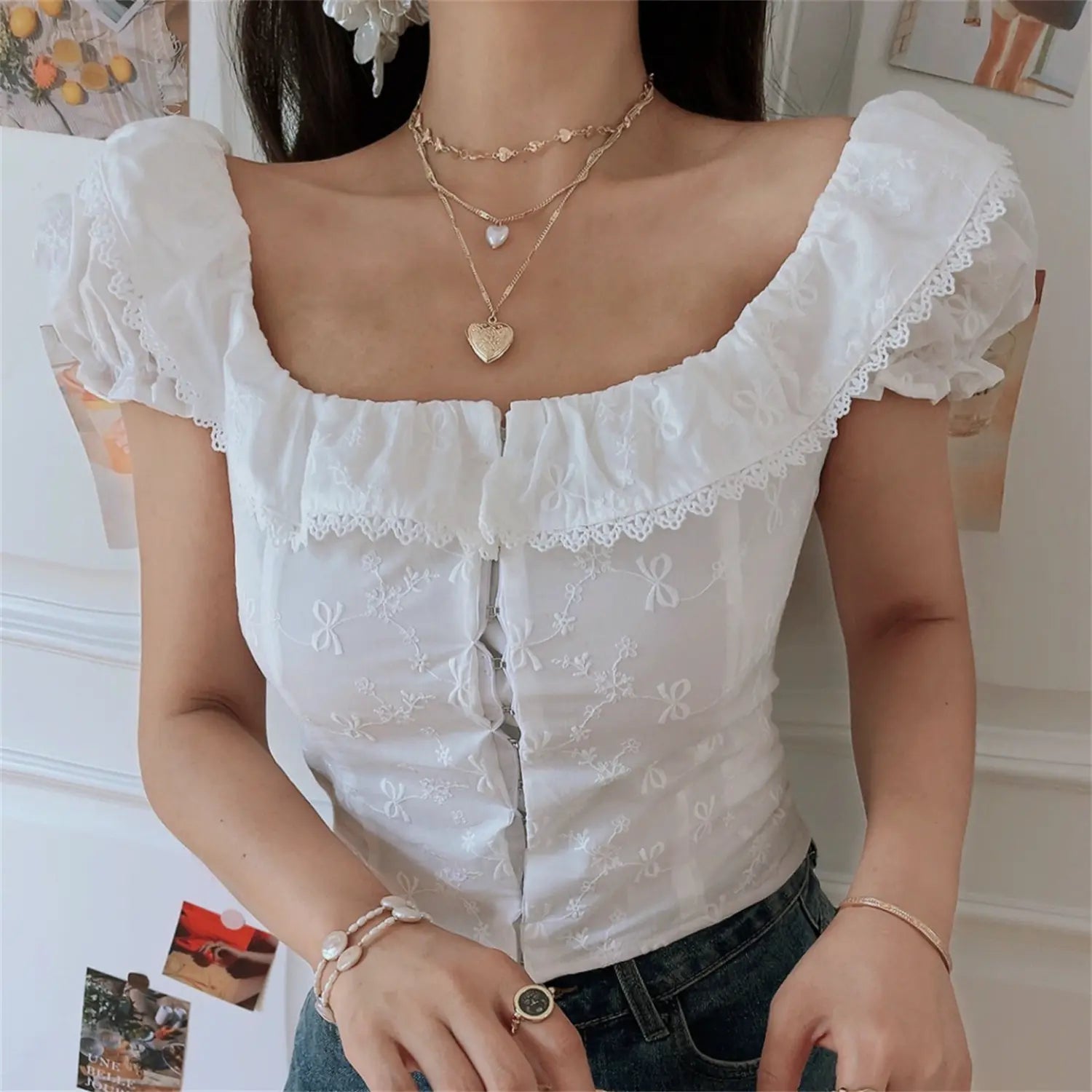 Lifestyle shot of model in the white embroidered square-neck camisole, holding a straw bag