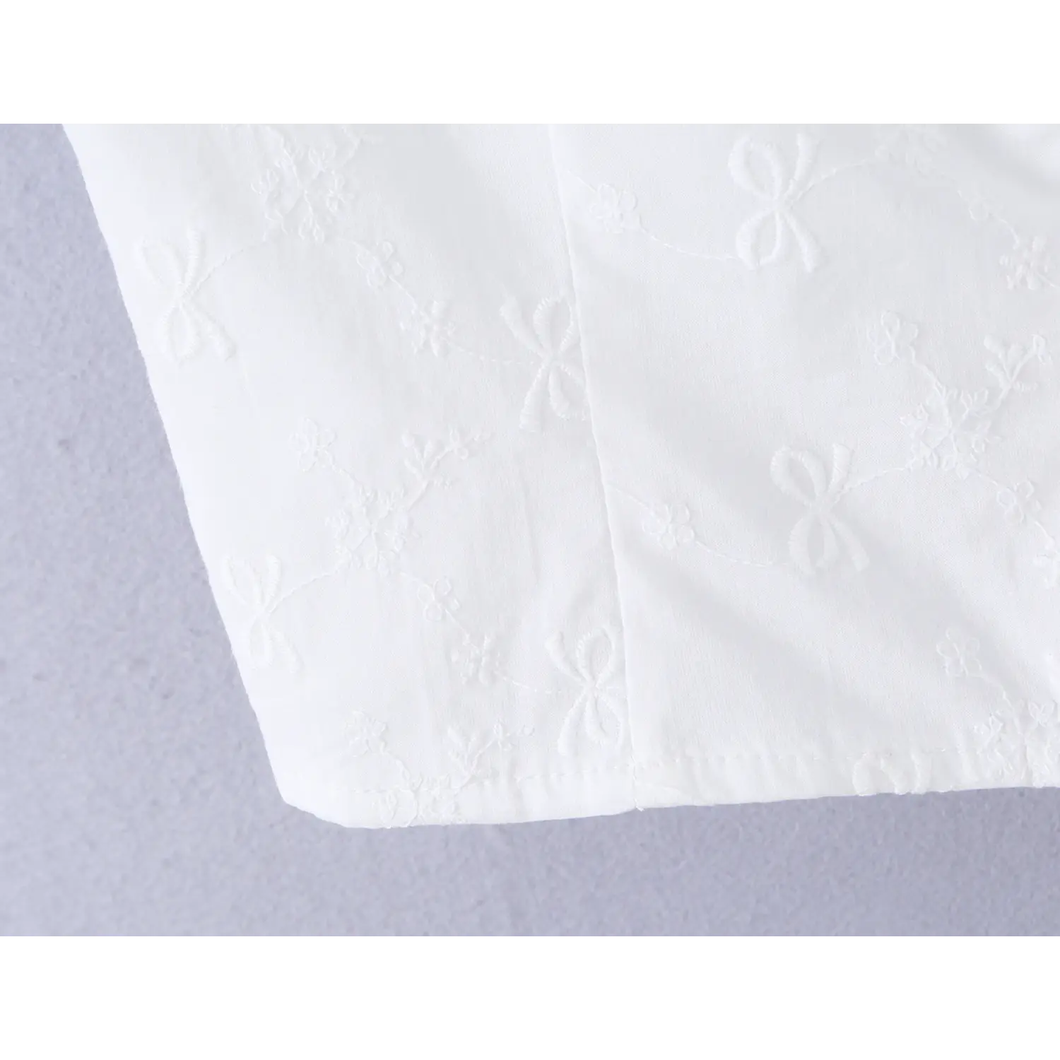 Close-up of the hem and embroidery details on the white embroidered camisole