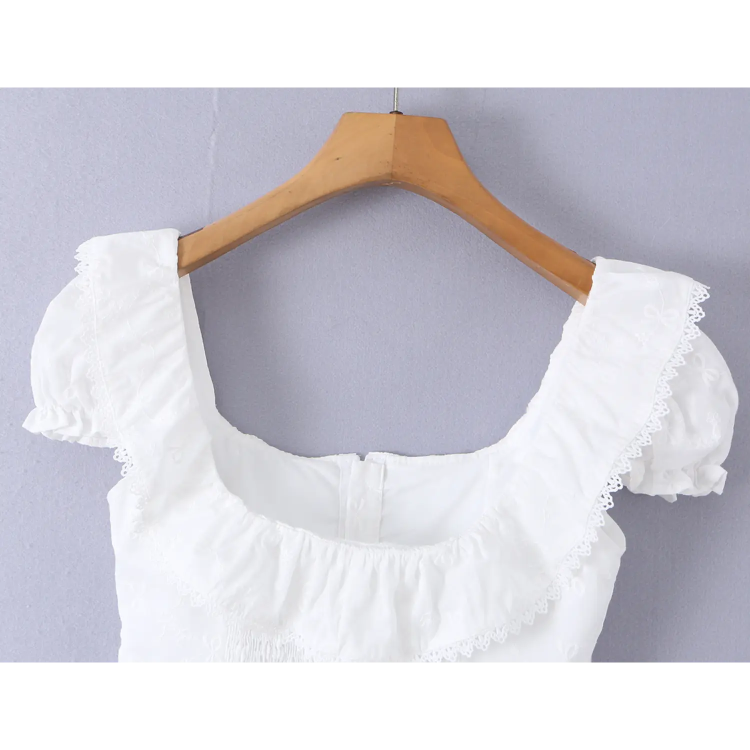 Close-up of the back neckline and lace trim on the white embroidered camisole