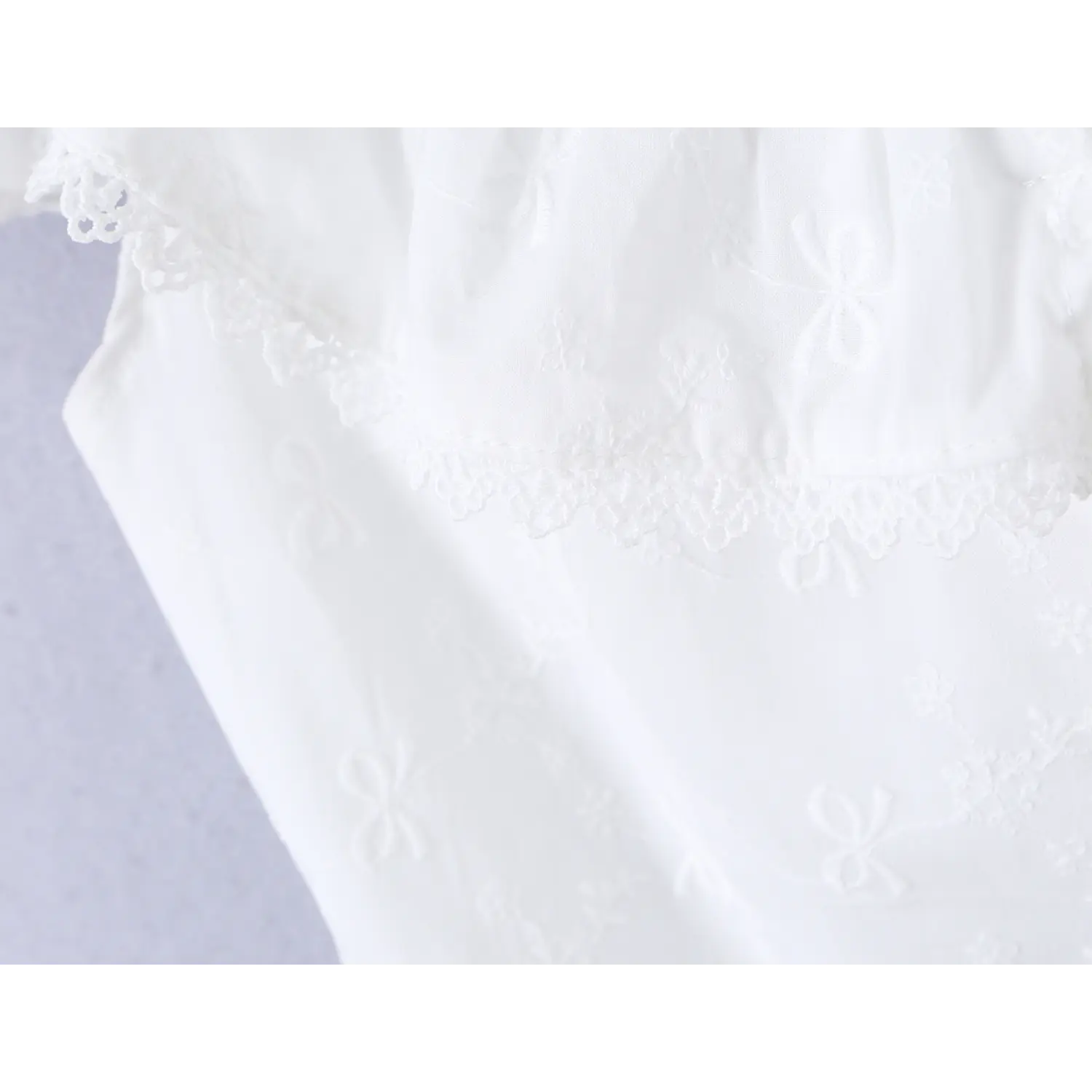 Close-up of the lace ruffle neckline on the white embroidered camisole