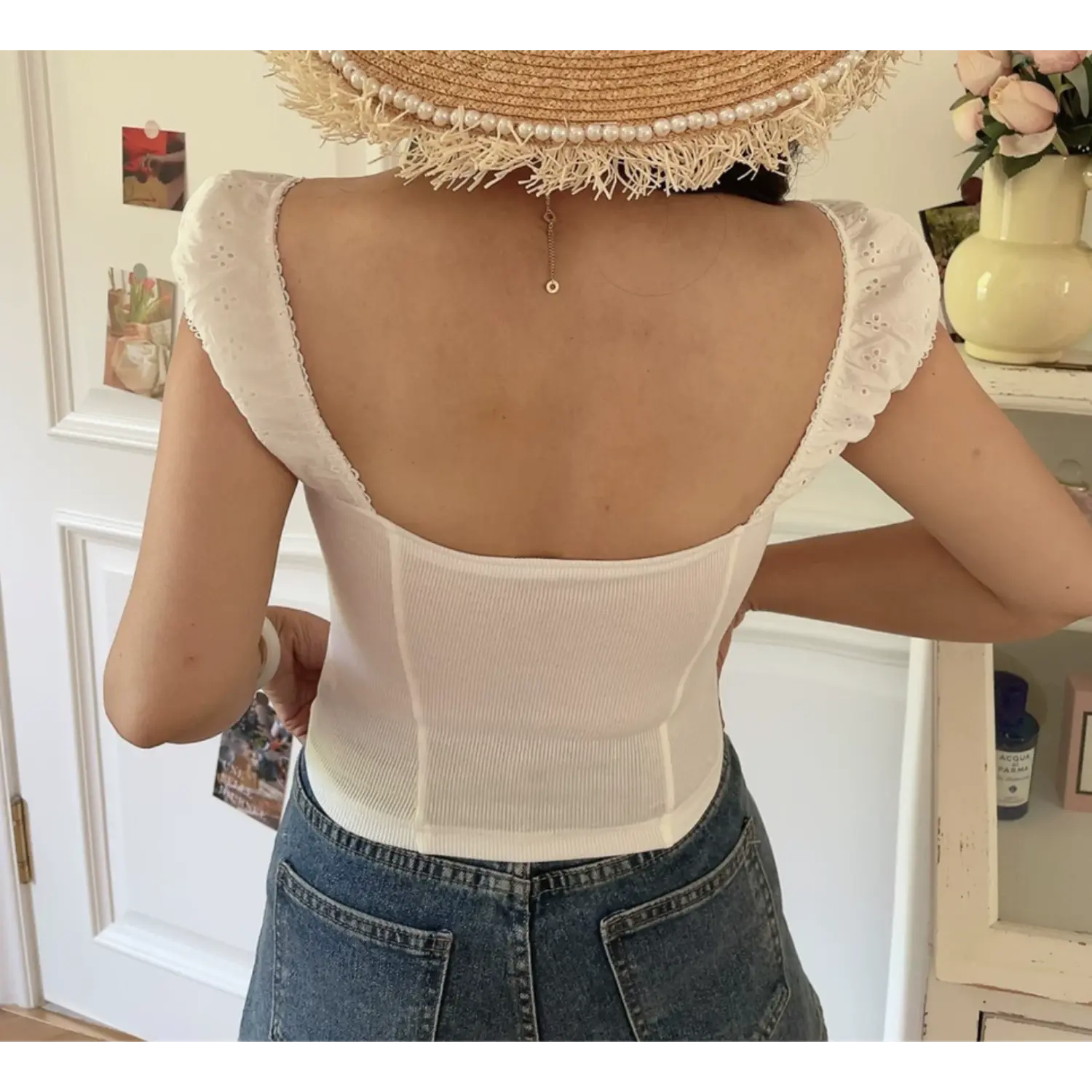 Lifestyle back shot of model wearing the white embroidered square-neck fitted top
