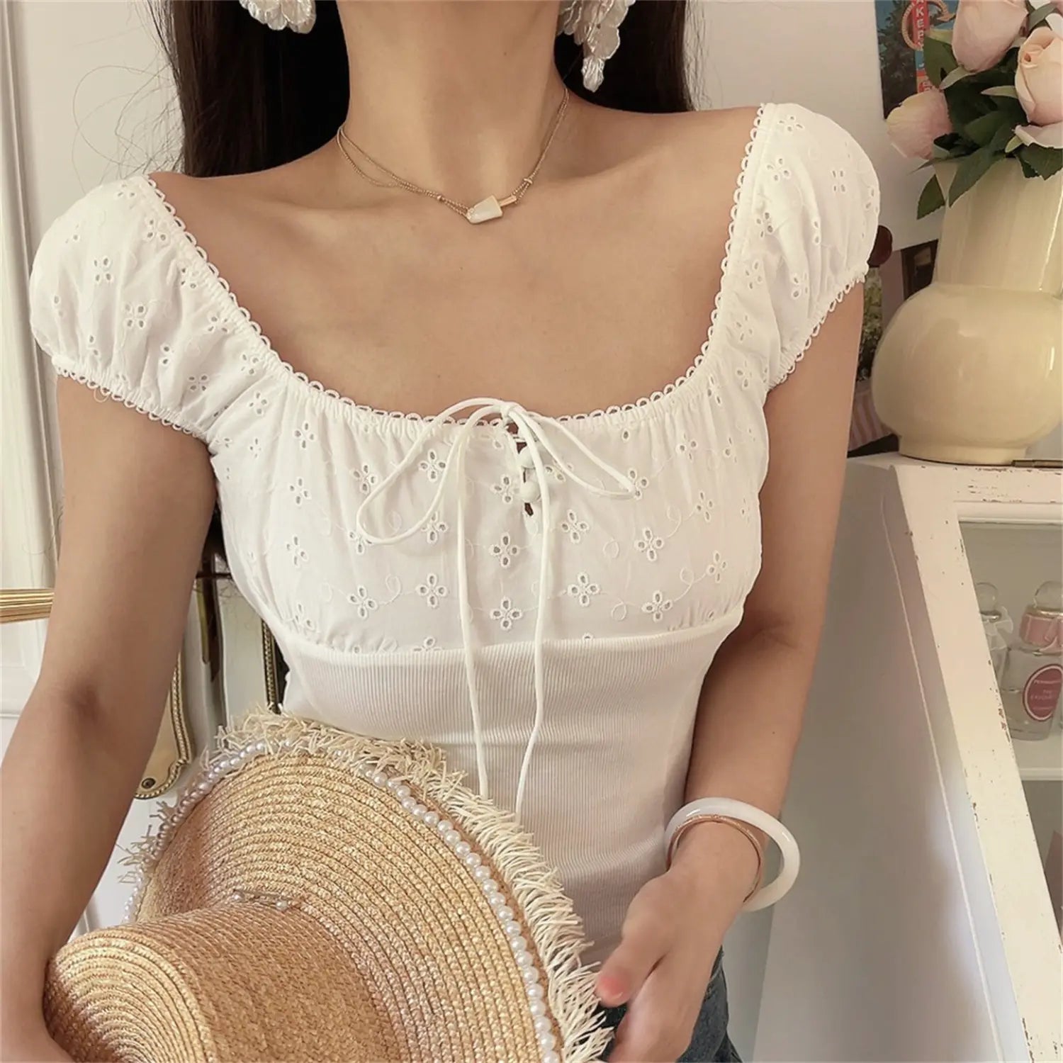 Close-up shot of model wearing the white embroidered square-neck top