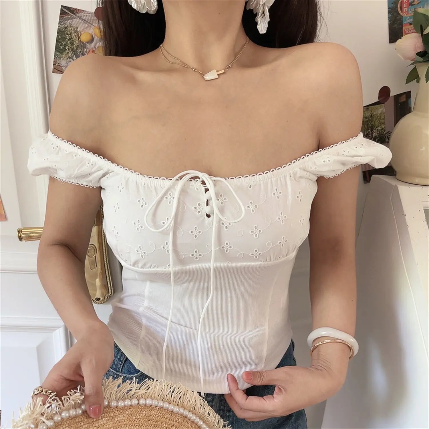 Off-shoulder lifestyle shot of model wearing the white embroidered square-neck top