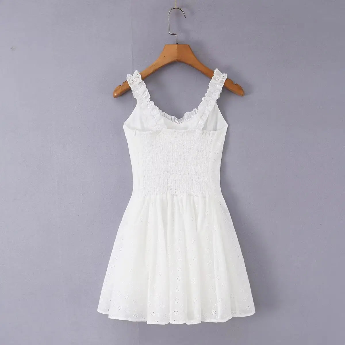 White eyelet embroidered cami skater dress hanging on wooden hanger, full back view