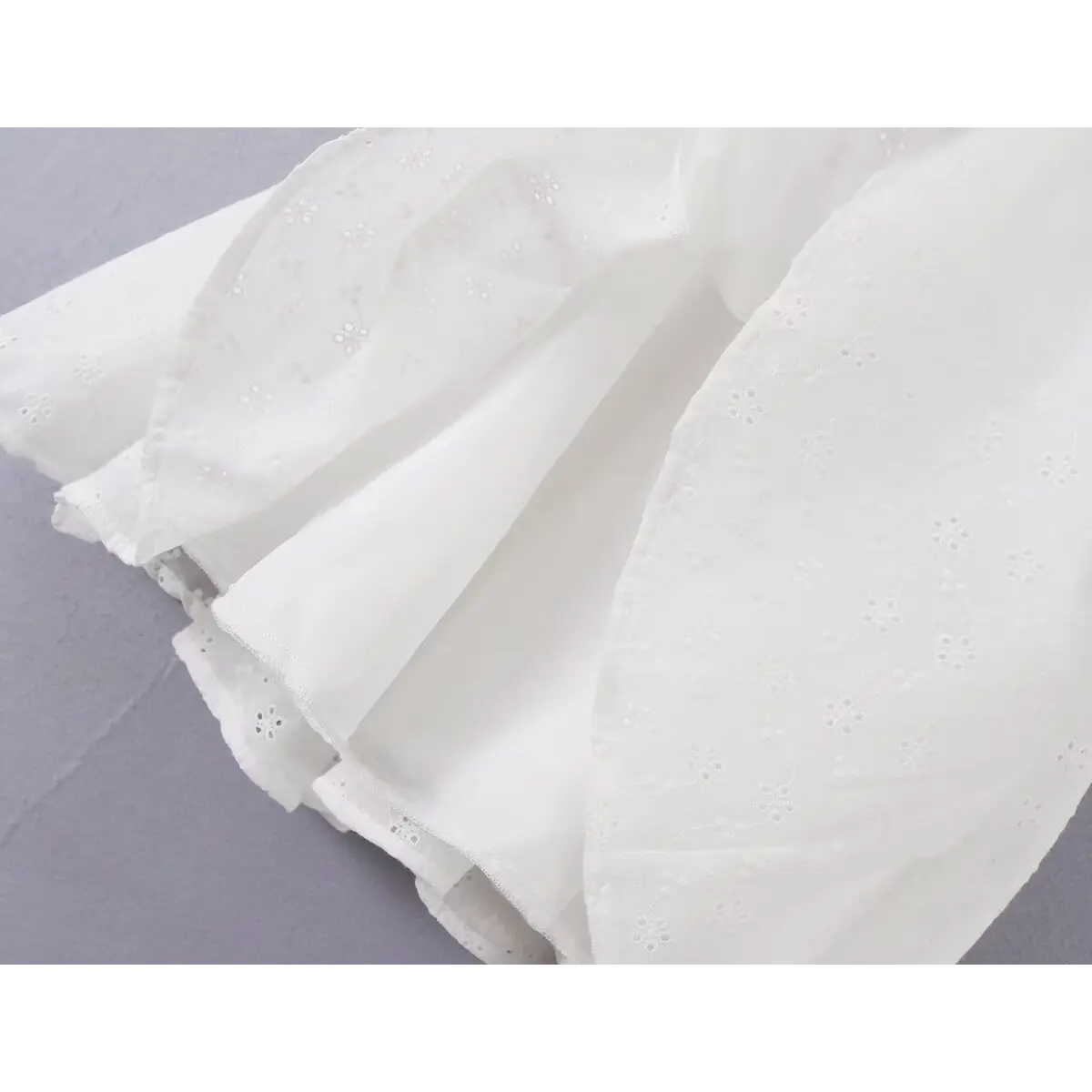 Close-up of the layered skirt construction and inner lining on the white eyelet dress