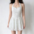 Model wearing a white halter-neck mini dress with eyelet embroidery, a sweetheart neckline, corset-style seams, and a ruffled hem.