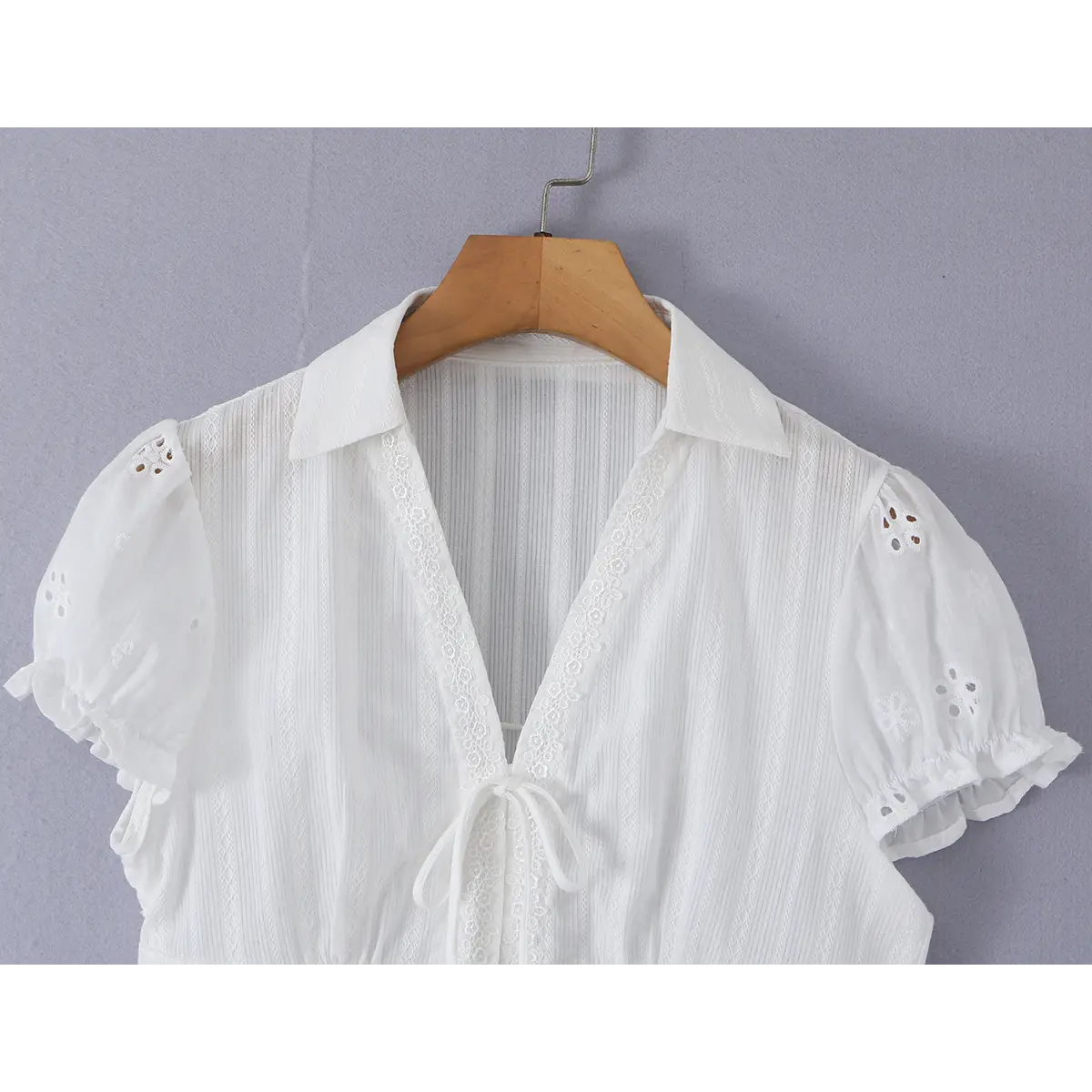Close-up detail of the back collar of a white eyelet lace bustier shirt, showing the pointed collar, vertical textured fabric, and puff sleeves.