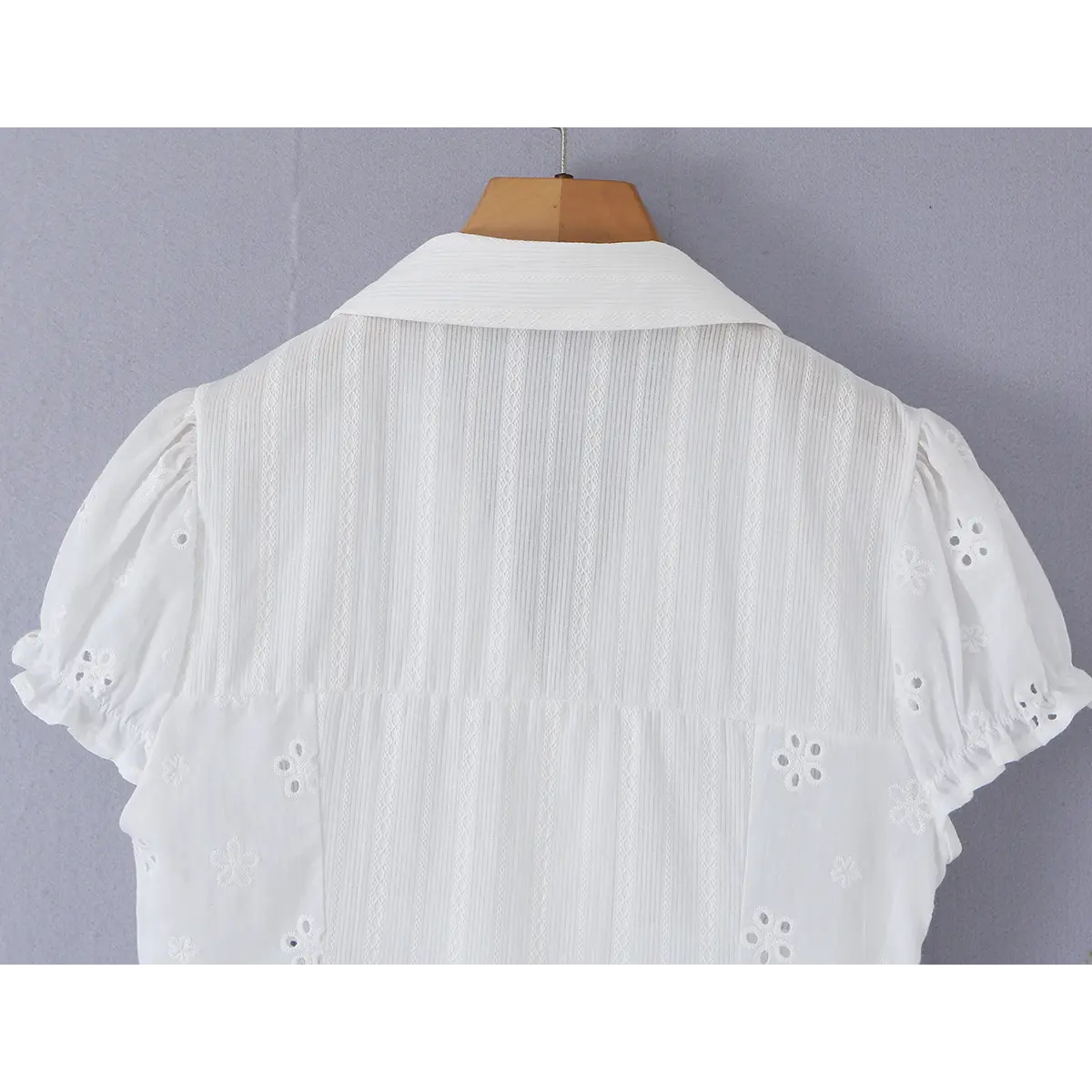 Close-up detail of the puff sleeve on a white eyelet lace bustier shirt, showing the eyelet embroidery and ruffled hem.