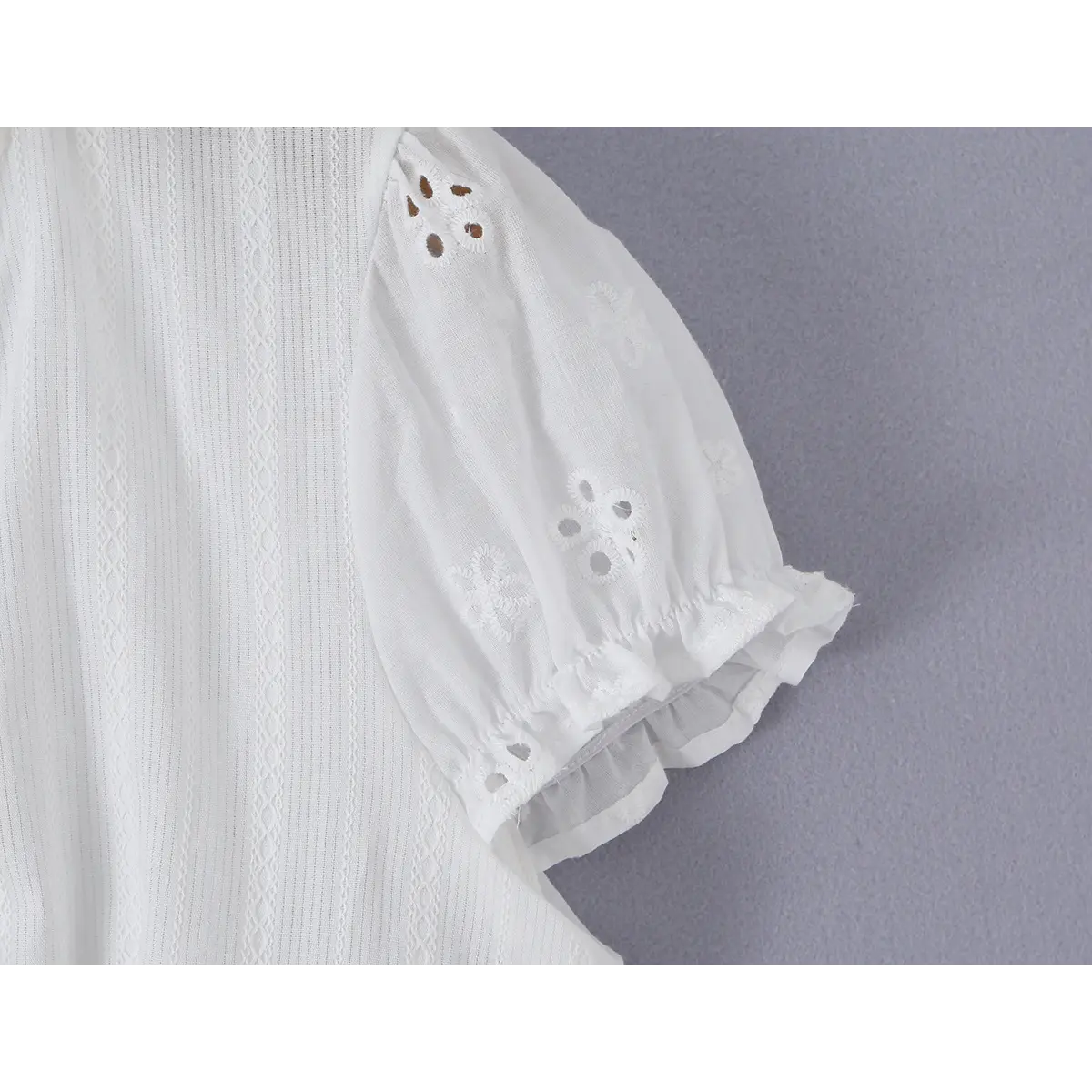 Close-up detail of the front tie closure on a white eyelet lace bustier shirt, showing the lace trim and tied ribbon.