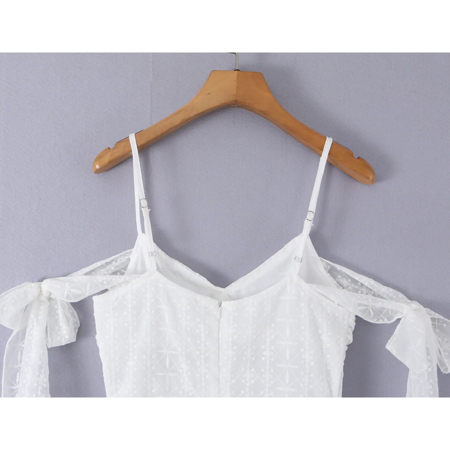 White floral eyelet off-shoulder mini dress wood hanger back full shot, adjustable slider thin straps center invisible zipper arm tie bows fitted waist back panel craft overview