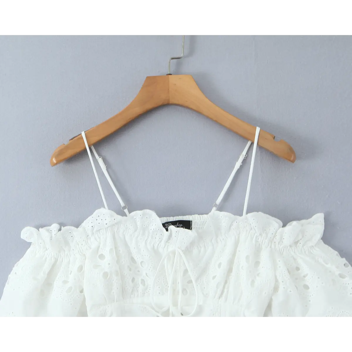 Full front view of white eyelet top with off-shoulder puff sleeves and corset lace-up front.