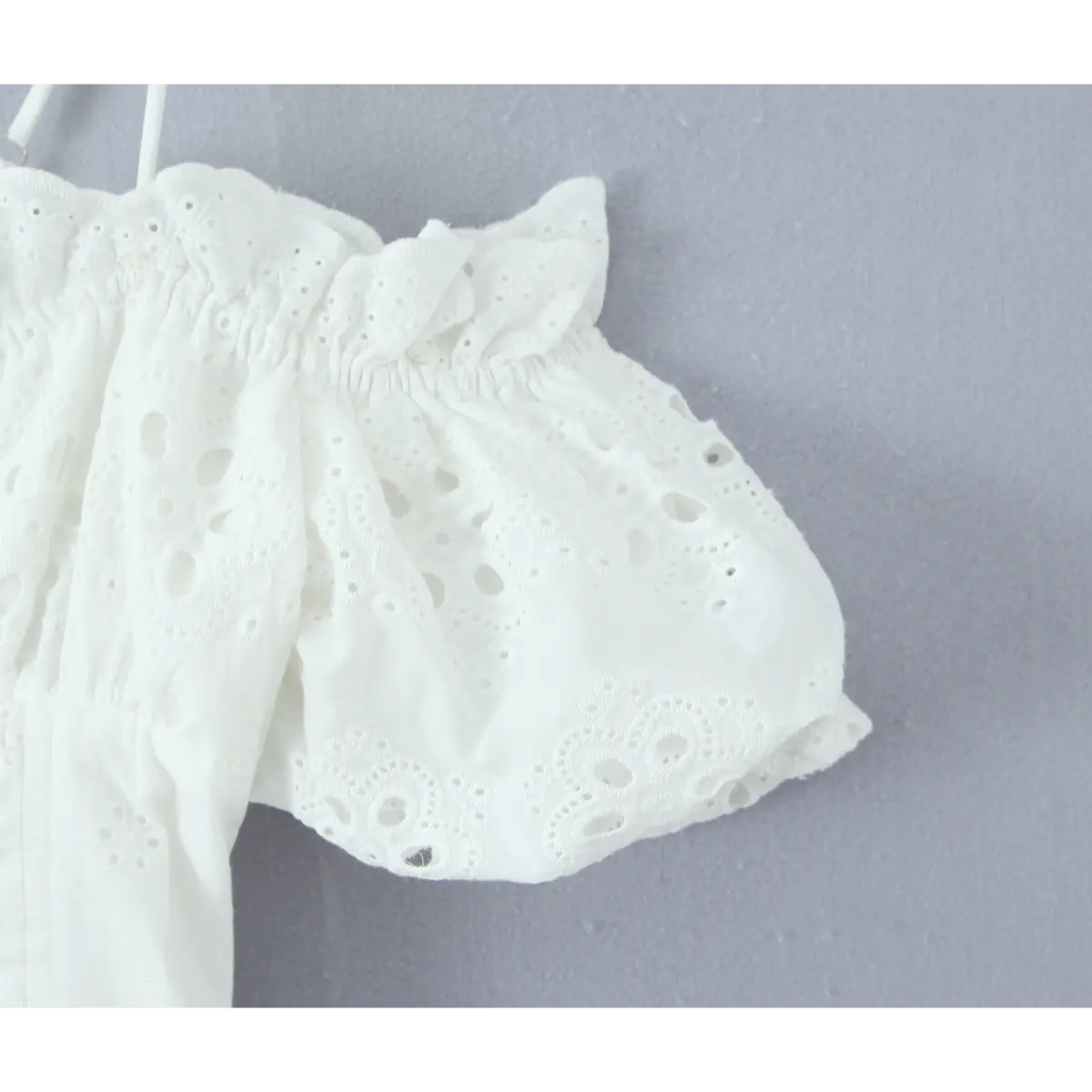 Close-up of puff sleeve with eyelet embroidery and ruffled elasticated edge.
