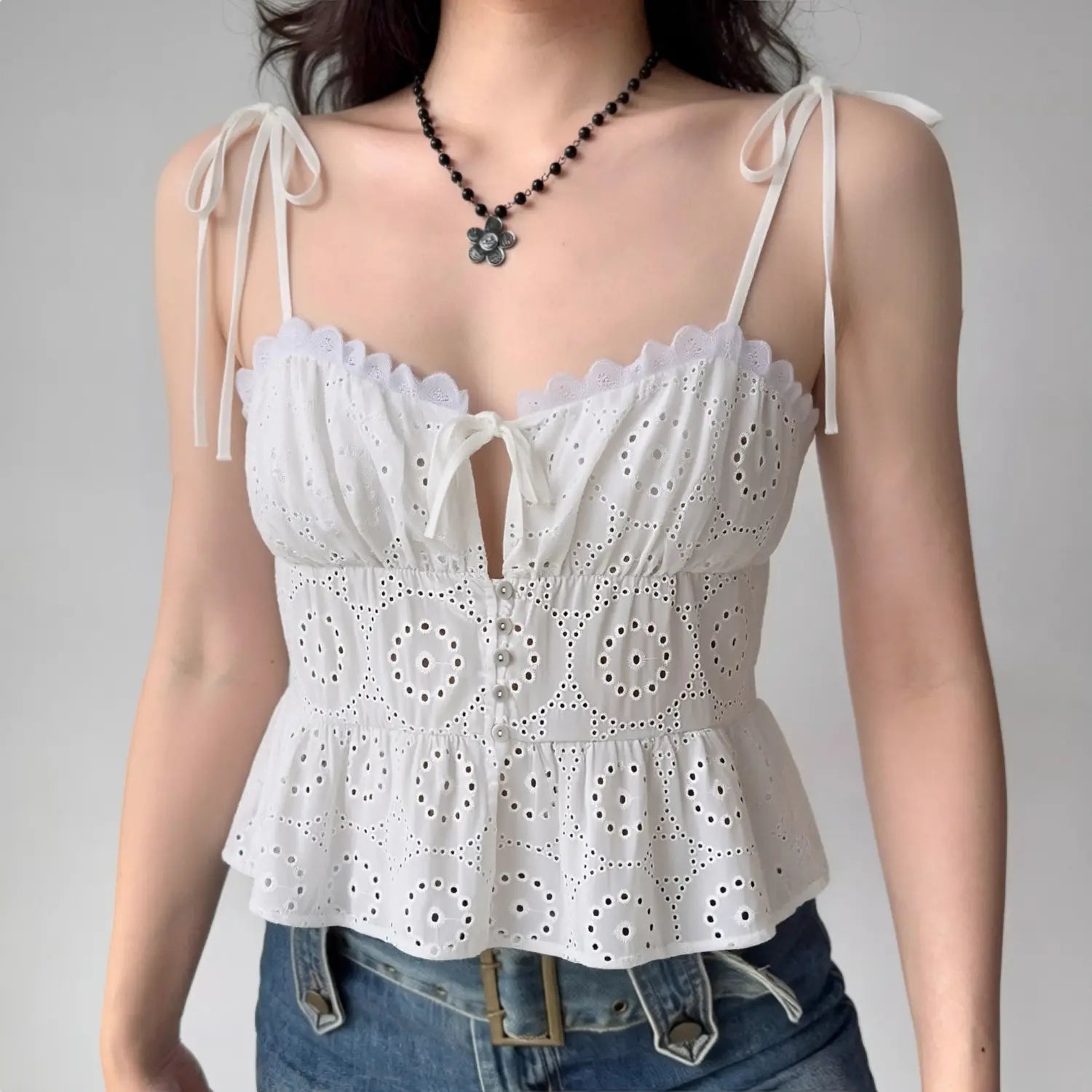 Lifestyle shot of model wearing the white eyelet peplum cami top with jeans, showing the tiered silhouette and sweetheart neckline