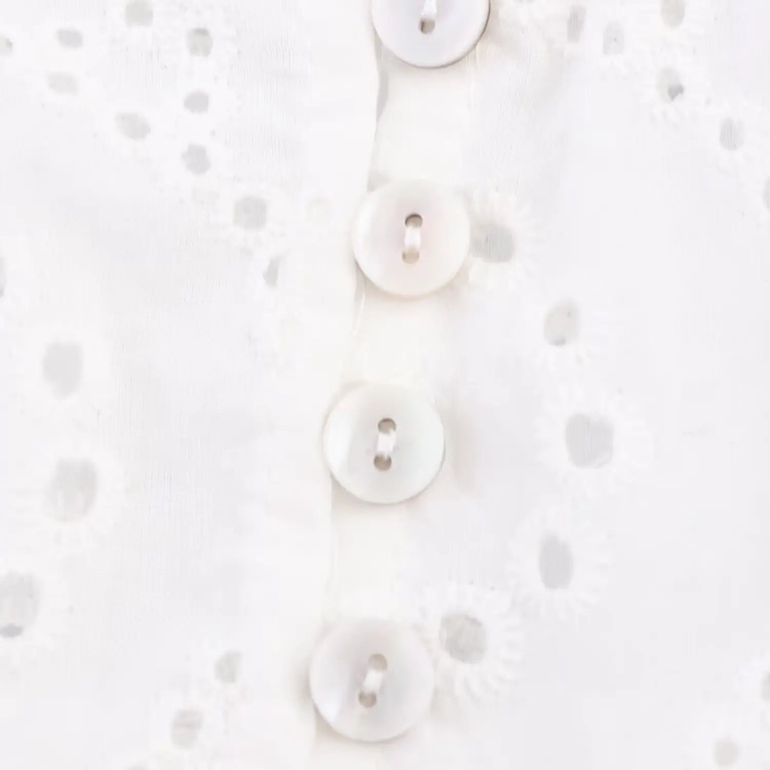 Close-up of the white shell buttons on the front placket of the eyelet cami