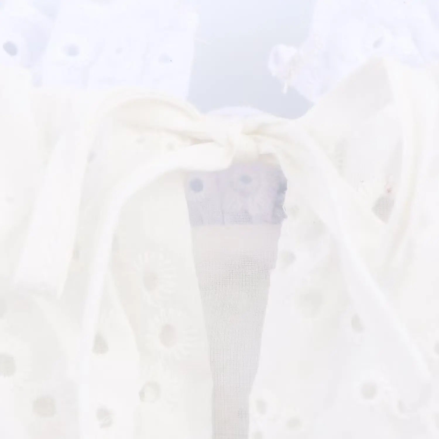  Close-up of the front tie knot and keyhole cutout on the white eyelet cami top