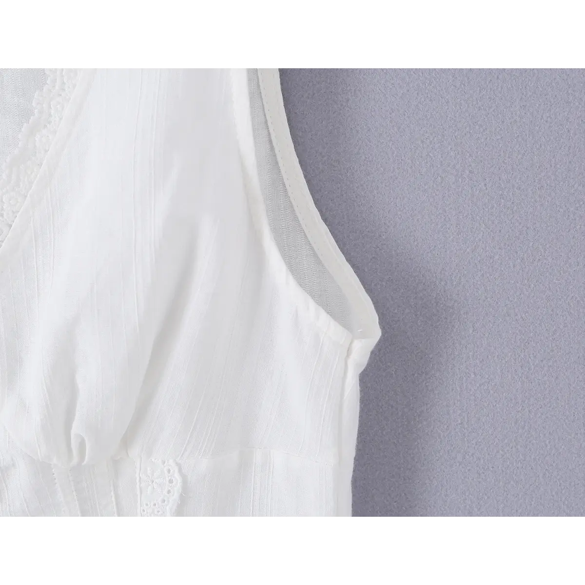 Close-up detail of the armhole on a white ribbed bustier tank top, showing the lace-trimmed edge and textured fabric.