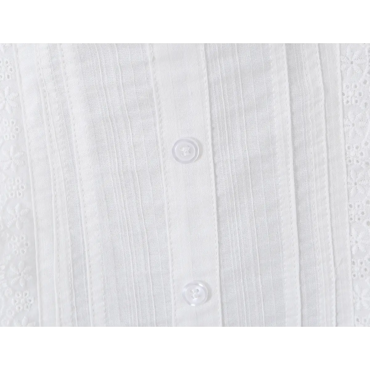 Close-up detail of the buttons on a white ribbed bustier tank top, showing the transparent buttons and textured fabric.