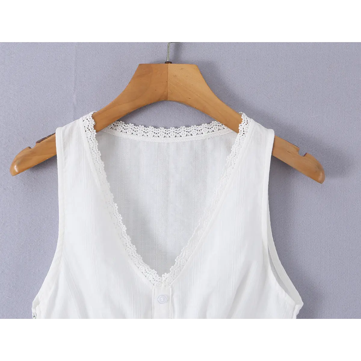 Close-up detail of the neckline on a white ribbed bustier tank top, showing the lace trim and V-neck shape.