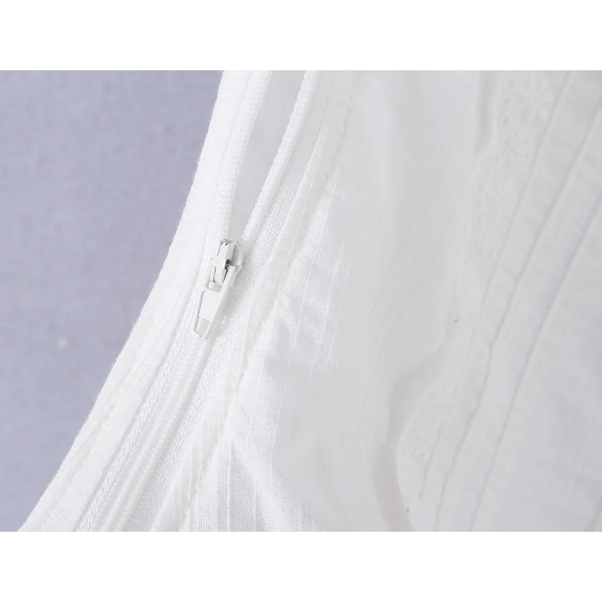Close-up detail of the side zipper on a white ribbed bustier tank top, showing the invisible zipper and fabric construction.