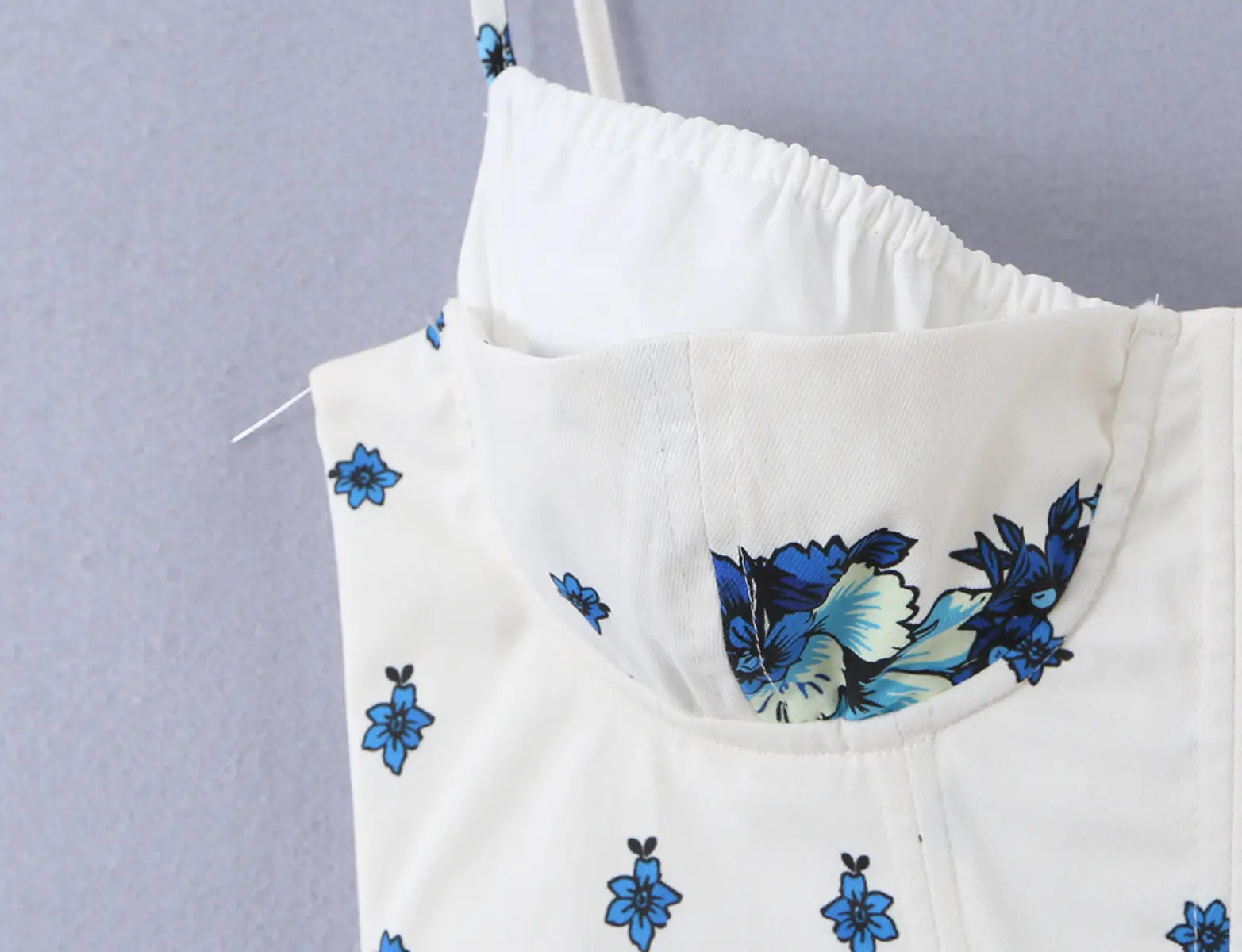 Close-up of the smocked back panel and floral print on the white cami top