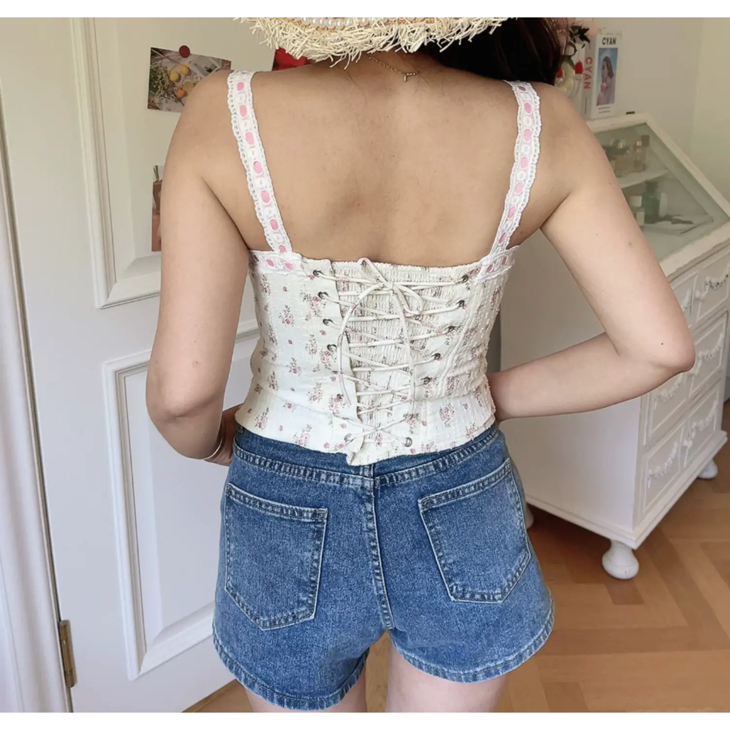 Lifestyle back shot of model wearing white floral print camisole with lace-up corset back