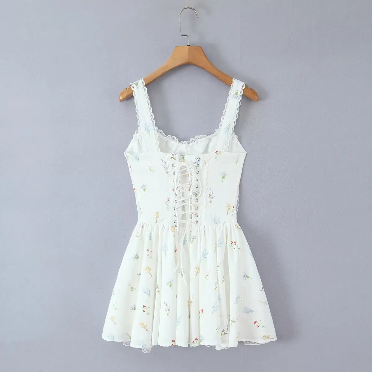Back view of the dress, showing the lace-up corset closure, floral print, and lace trim at the hem.