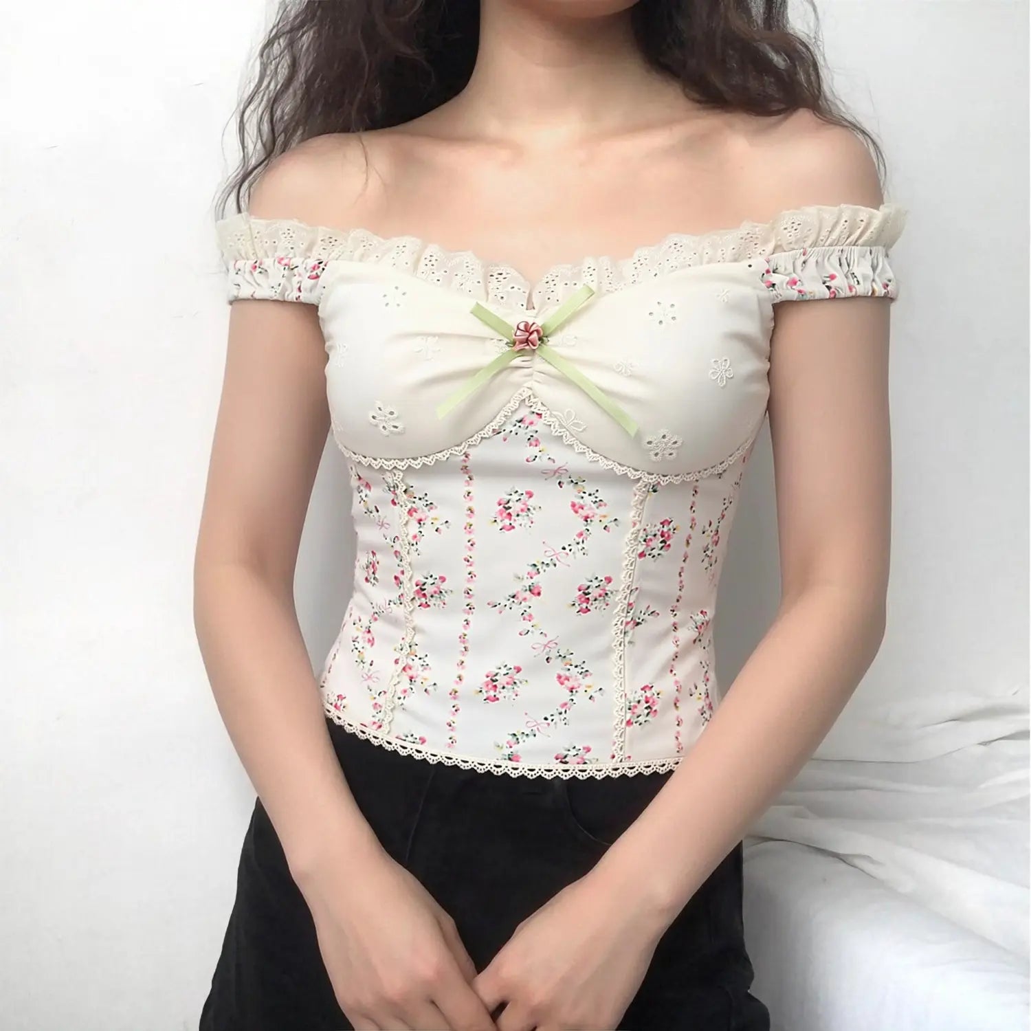 Indoor model front view off‑the‑shoulder white floral corset top green ribbon fabric rose bust detail eyelet lace trim