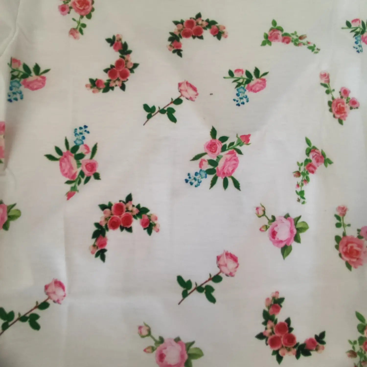 Extreme close‑up fabric texture of all over pink rose floral print on white knit top
