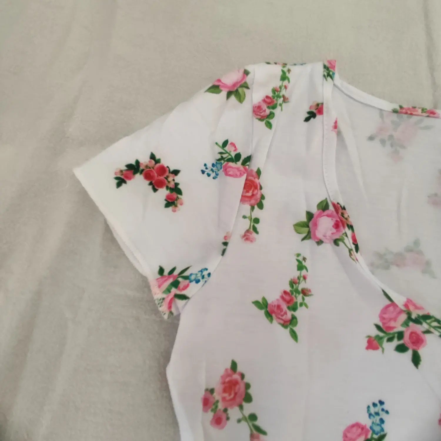 Close‑up shoulder and short sleeve view white rose floral print tie front crop top