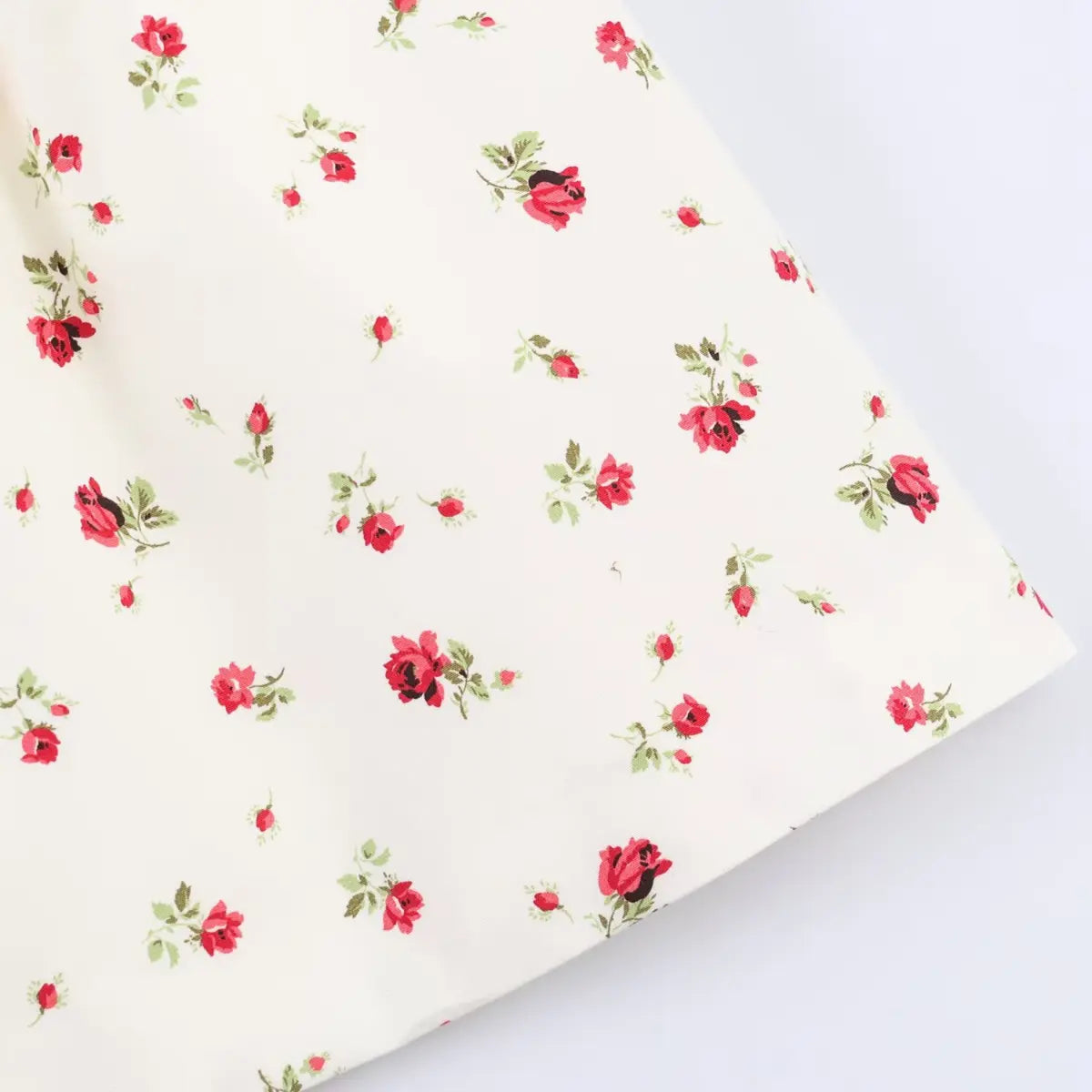 Close-up of the dress's outer fabric, showcasing the fine weave and scattered rose print.