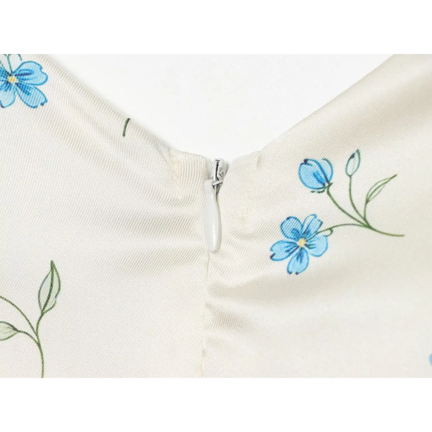 Close-up invisible zipper on V back, white satin fabric with blue ditsy floral print