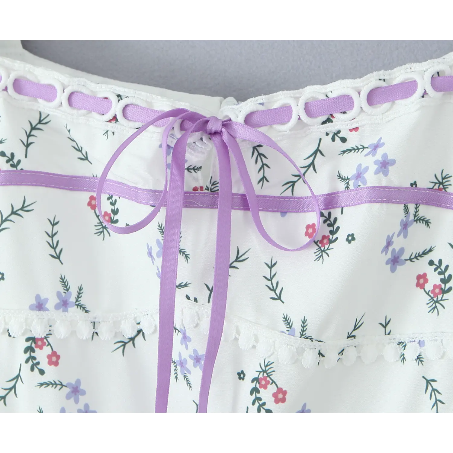 Close‑up front purple satin ribbon bow, eyelet lace trim, ditsy floral printed dress bodice detail