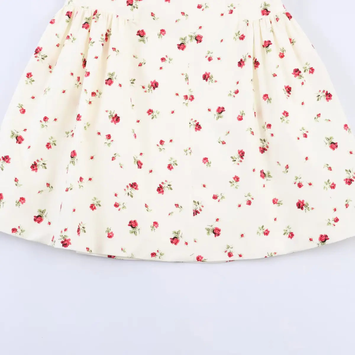 Close-up of the dress's gathered A-line skirt, showing the red rose print and smooth fabric drape.